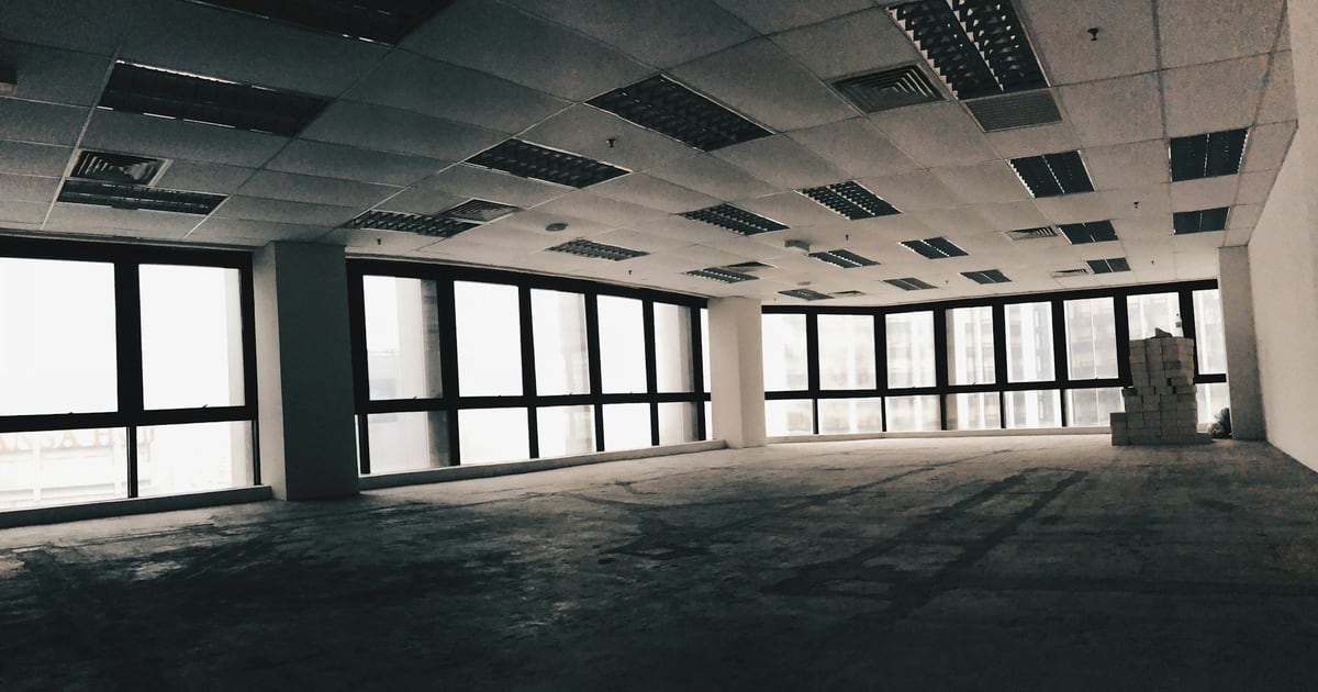 An empty office floor with bare concrete and a row of windows, no desks or people