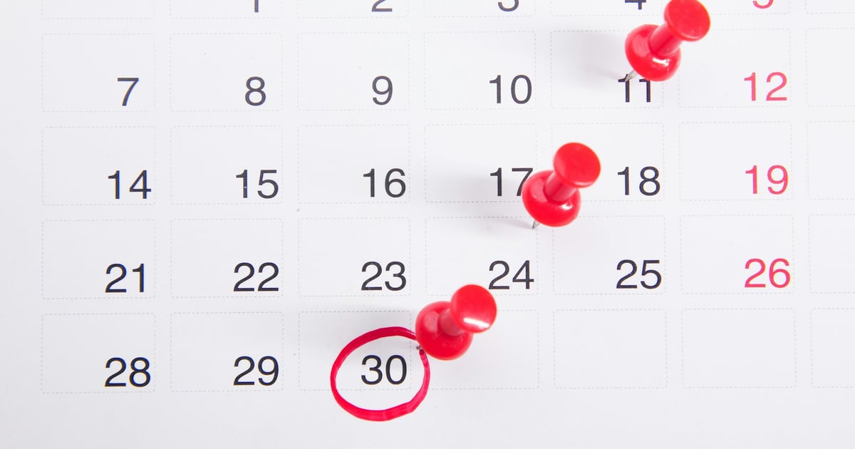 A wall calendar with red pins in several dates and the 30th circled in red